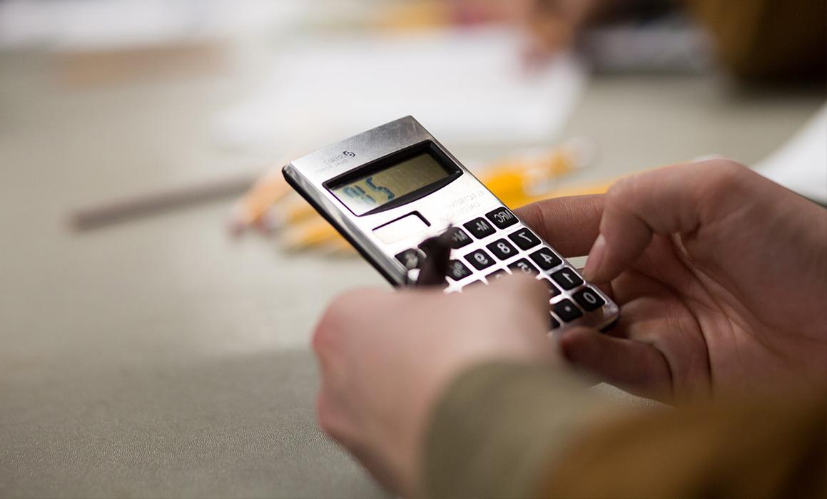 Closeup of two hands holding onto a calculator