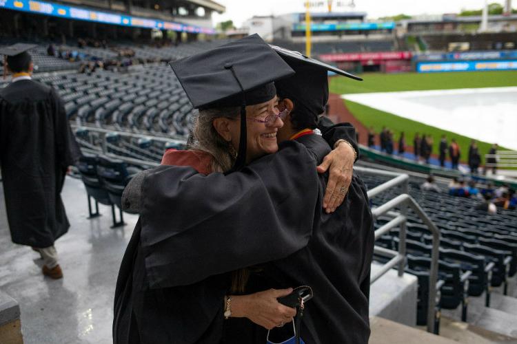 Two people in regalia hugging