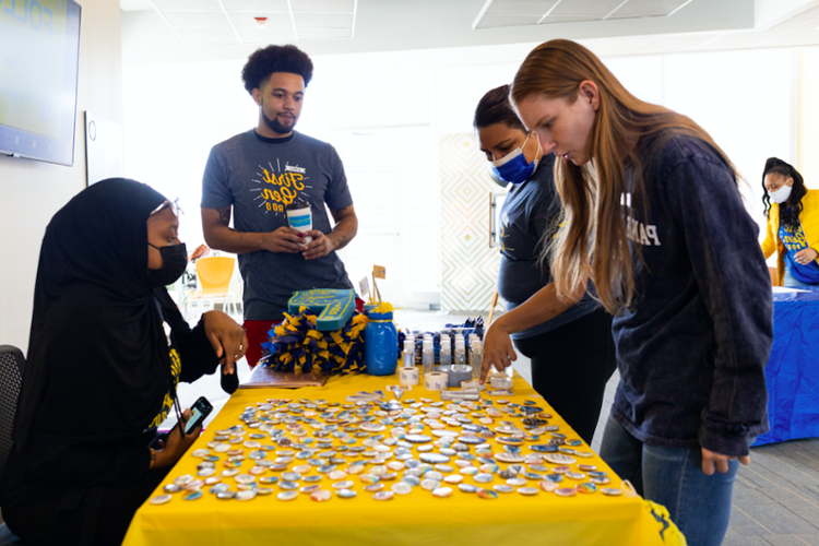 学生s gather around a table for more information and First Gen Roo swag.