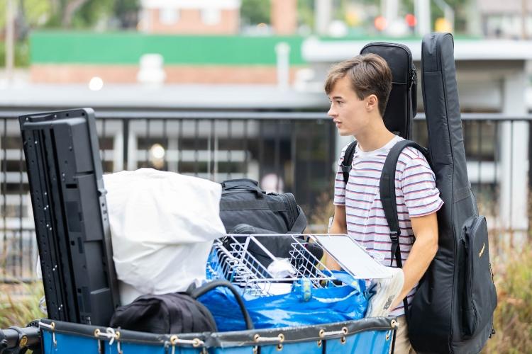 A student pushes a bin during move in at Oak Street Residence Hall