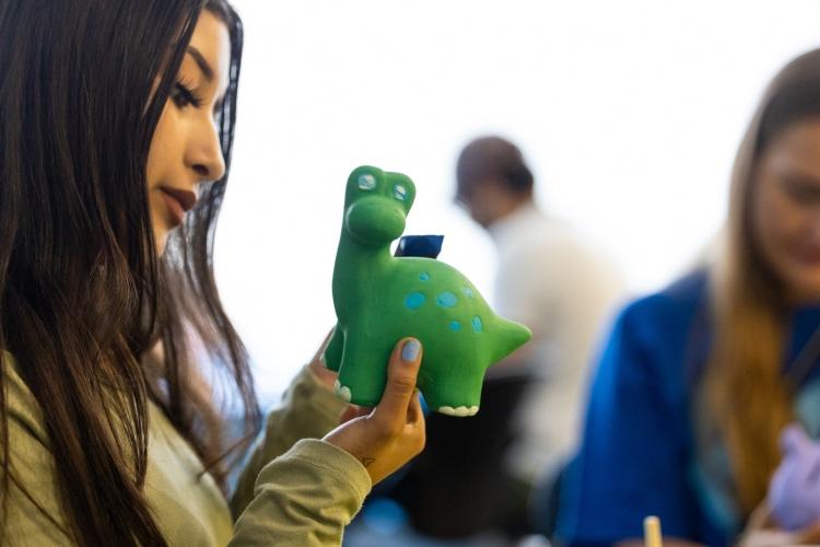 A student paints a green dinosaur