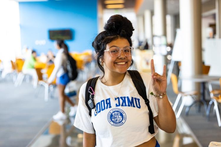 A student smiles with a roo up gesture