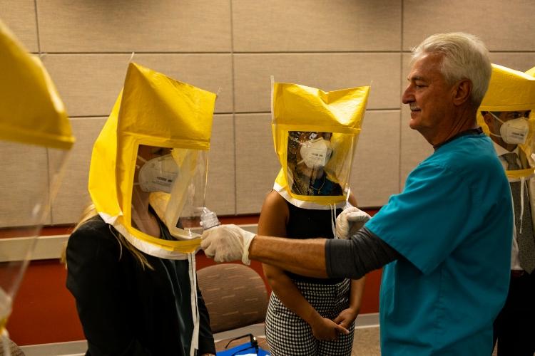 A professor stands in front of a line of students who are wearing personal protective equipment