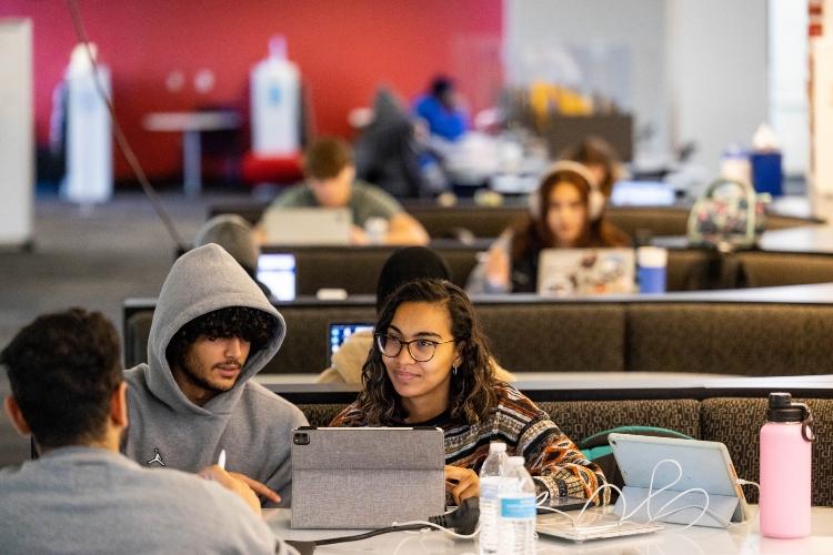 Two students look at a laptop at a table at Miller Nichols library