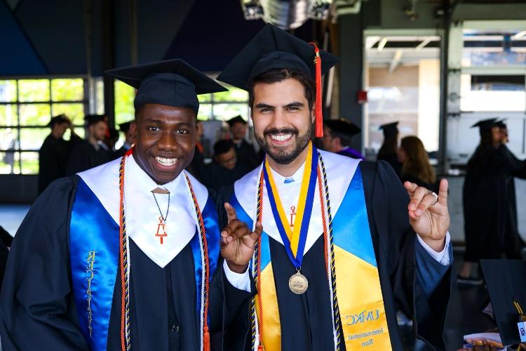 Two graduates doing the Roo Up hand gesture