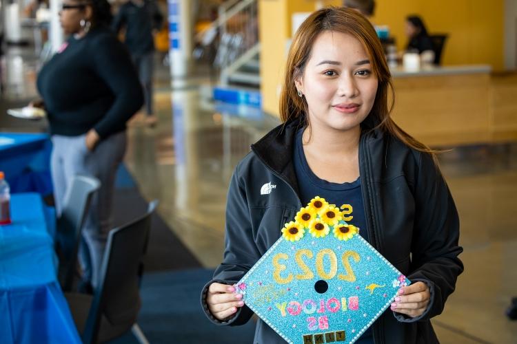 A first generation college student holds her graduation gap, which she has just decorated, inside the UMKC student union