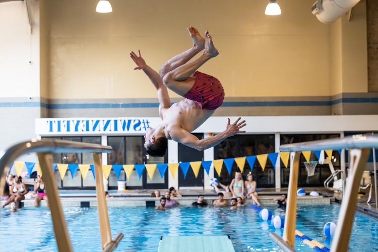 A male student jumping from a board at Swinney Center.