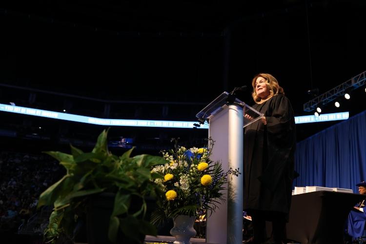 Esther George stands at a podium in regalia 