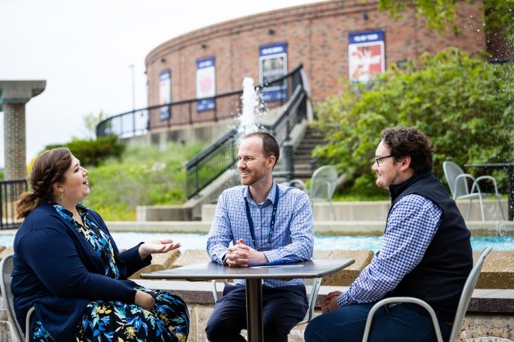 Roslinde Rivera sits outside at Starlight at a table with two other people who are smiling at her while she speaks.