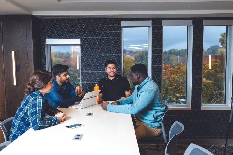 Students sit around large tables in a new, upgraded space in Bloch Heritage Hall