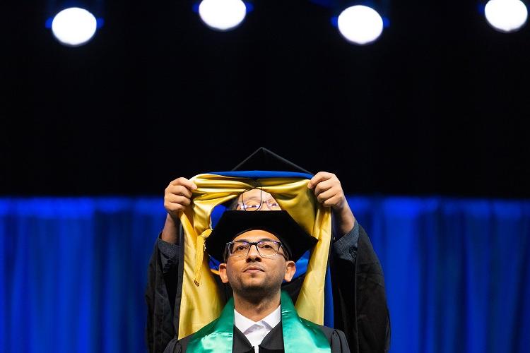 Graduating student gets hooded on stage