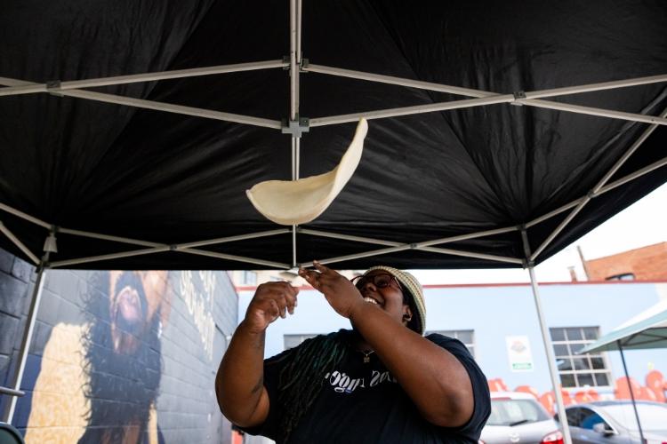 Devoured Pizza''s Jhy Coutler tosses pizza dough in the air.