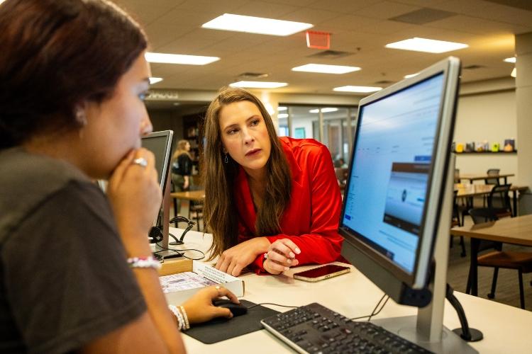 Meghan Jaben leans over a desk to look at a screen at Miller Nichols Library