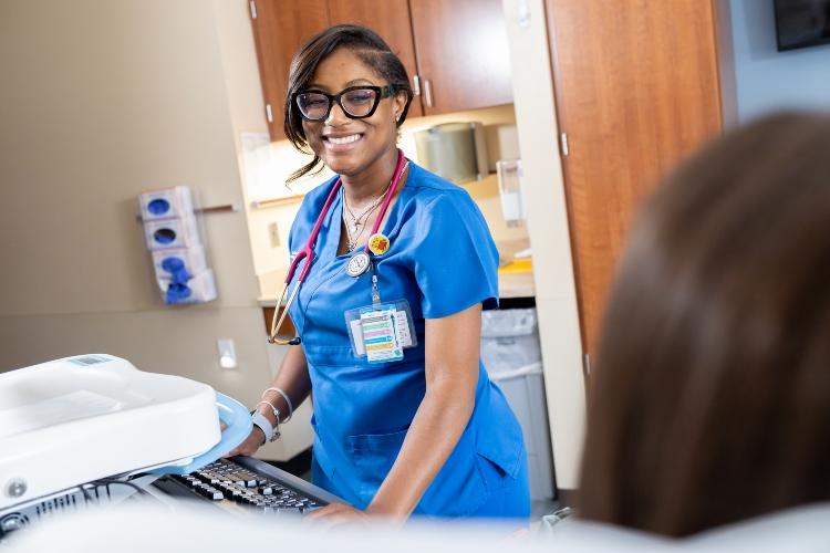 Tatyana Charles smiles at a patient inside a hospital room at University Health