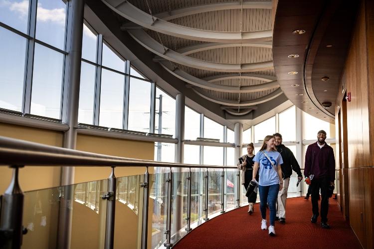 UMKC students walking down the red carpeted hallway on the second floor of the Chiefs training facility by the stairs