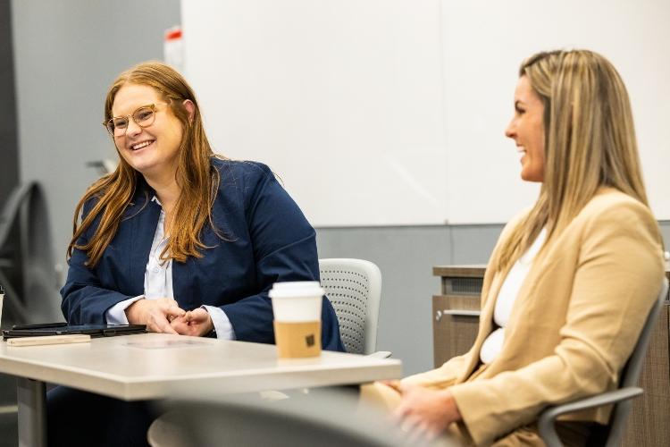 Annmarie Orlando and her mentor Kylie Dewees smile sitting together at at a table